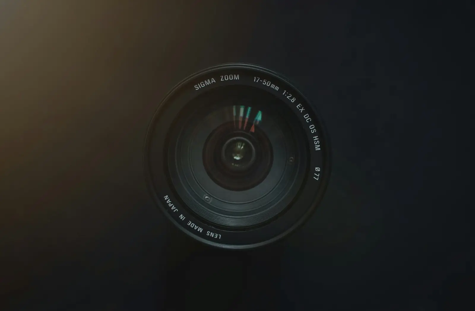 A camera lens resting face-up on a dark surface