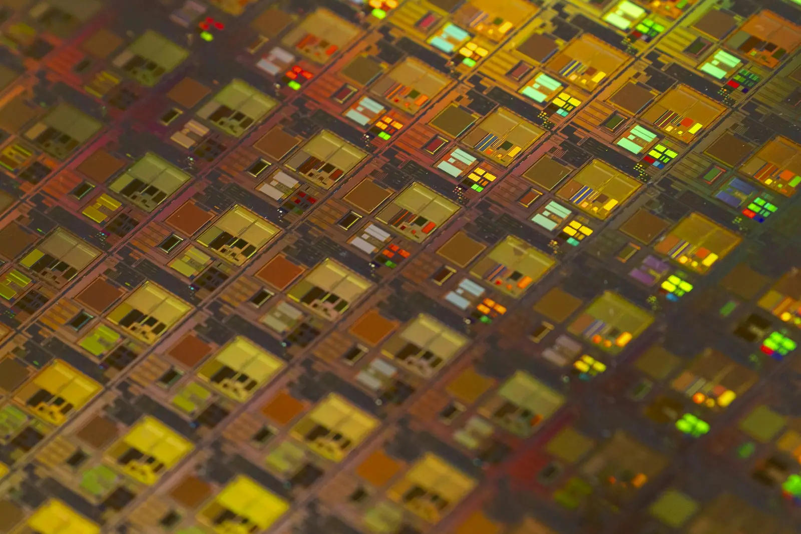 Macro photograph of a silicon wafer, its chip dies glowing amber and gold